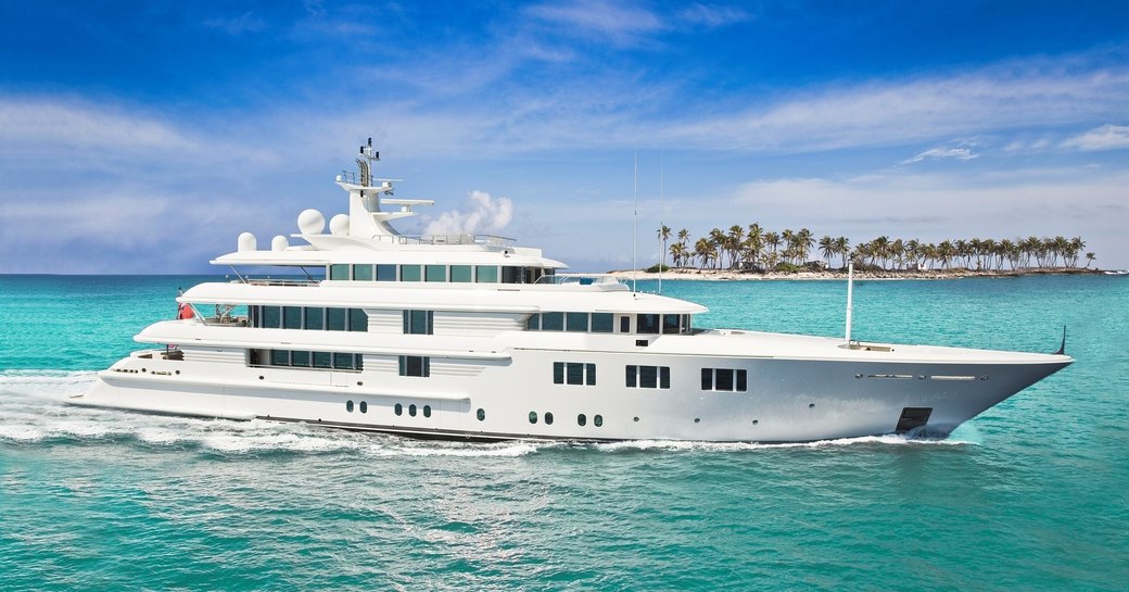 Lady E before her refit, on crystal clear with blue sky and beach coastline in background