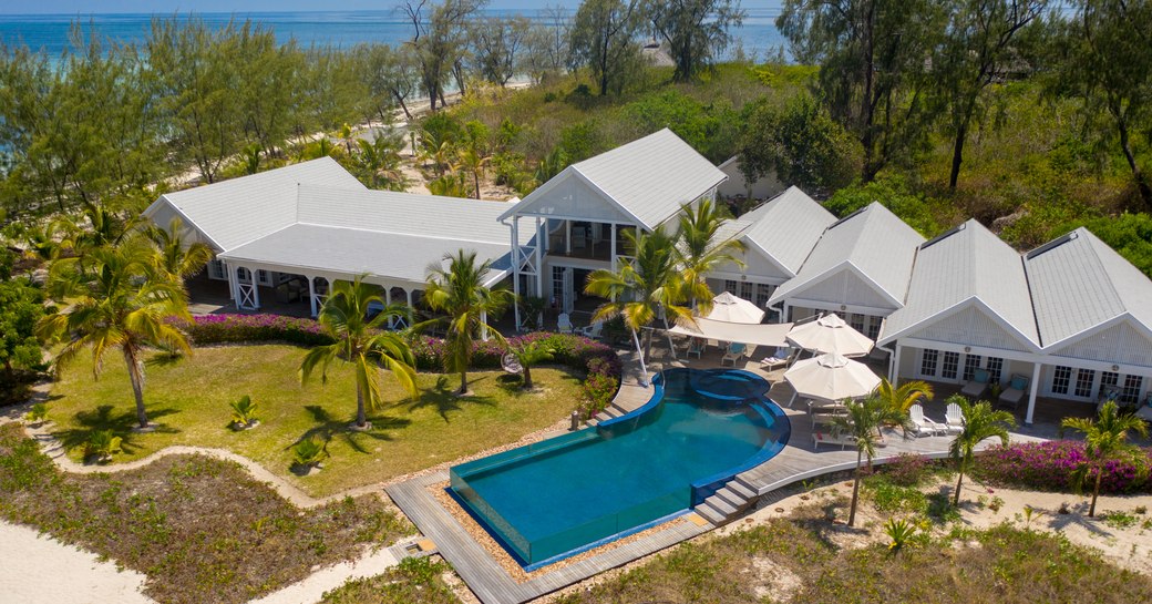 aerial shot of the villa on thanda island, with infinity pool and palm trees, as well as sandy strip of beach visible