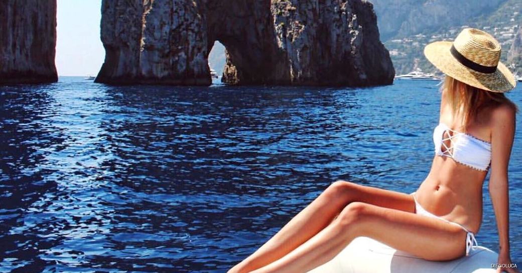 girl sat on the edge of the yacht looking out at amalfi coast