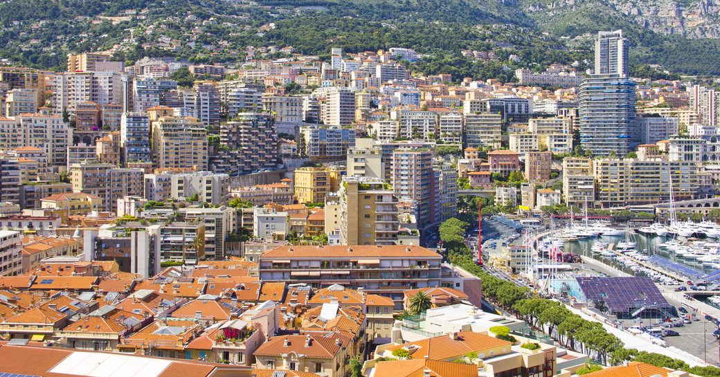 Overview of Monaco, view over the rooftops, with Port Hercule and superyachts visible to right hand side.