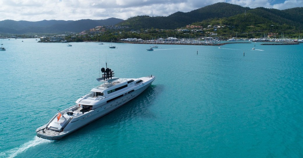 Superyacht cruises up to Coral Sea Marina Resort ahead of Australian Superyacht Rendezvous, with blue sea and green landscapes in background