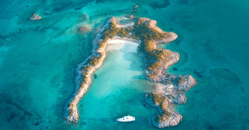 superyacht anchored next to a deserted island in the Bahamas