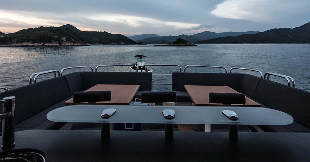 Comfortable seating and tables on deck of motor yacht Oksanchik with sea in background