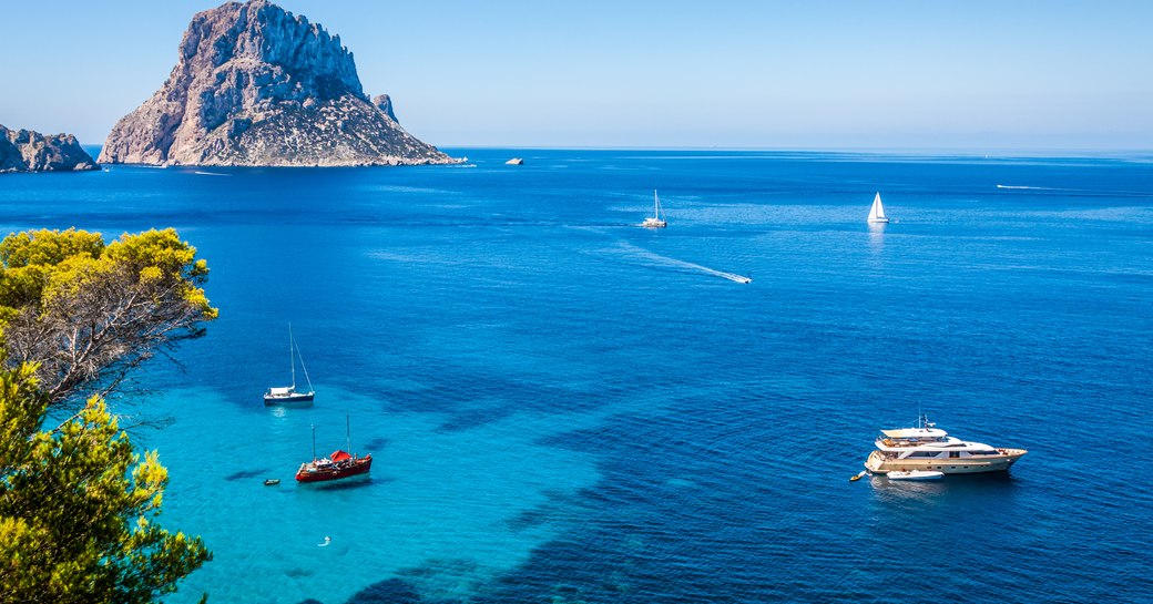 Yachts in Cala d'Hort, Ibiza. Clear blue water and rugged mountain in background