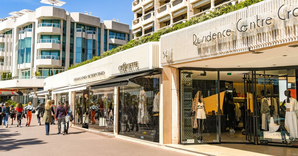 People walking past designer shops on the seafront in Cannes.