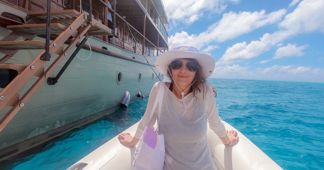 woman sits on tender next to luxury charter yacht over the rainbow in east africa