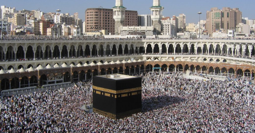 Overview of the pilgrimage site of Mecca, Saudi Arabia. Huge crowds gathering under a blue sky.
