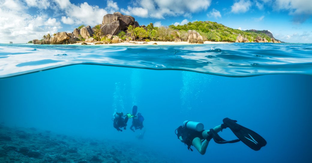 Divers below the surface in Seychelles exploring coral reefs