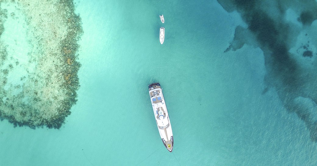 a superyacht anchors in a secluded spot nearby coral reef on a Bahamas yacht charter 