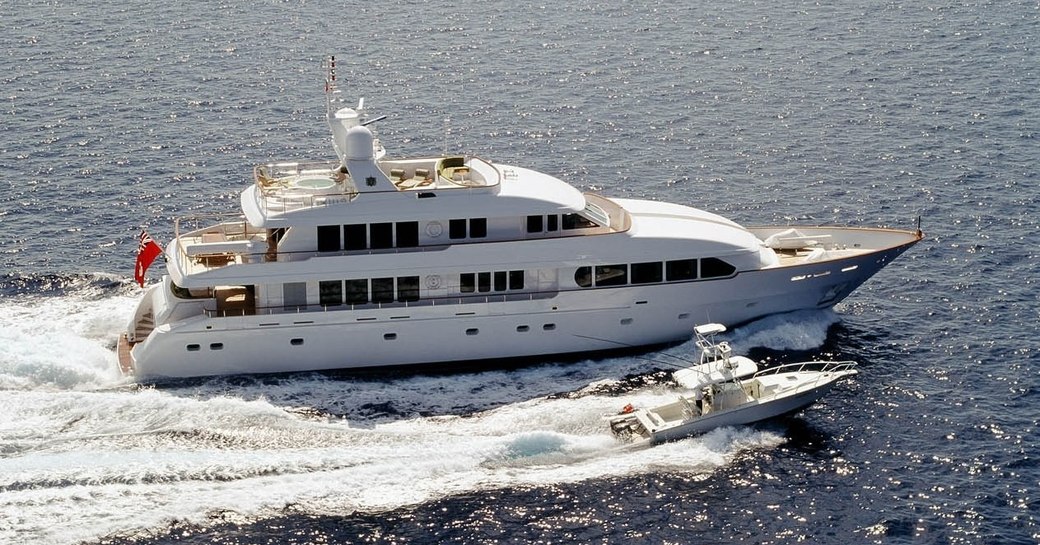 superyacht M4 cutting through the water with her tender on a Bahamas yacht charter