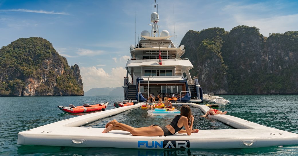 women relaxing on the large net pool next to heesen charter yacht lady azul