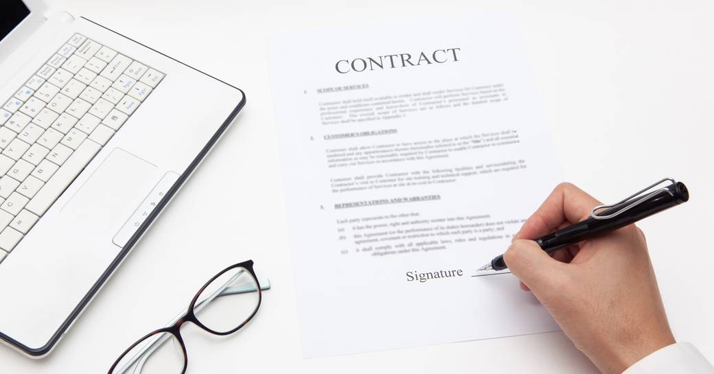 Signing a contract, with glasses and laptop nearby