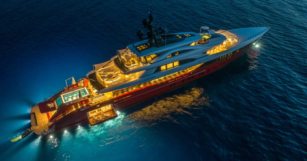 Aerial overhead view looking down on superyacht LEONA surrounded by sea at night.
