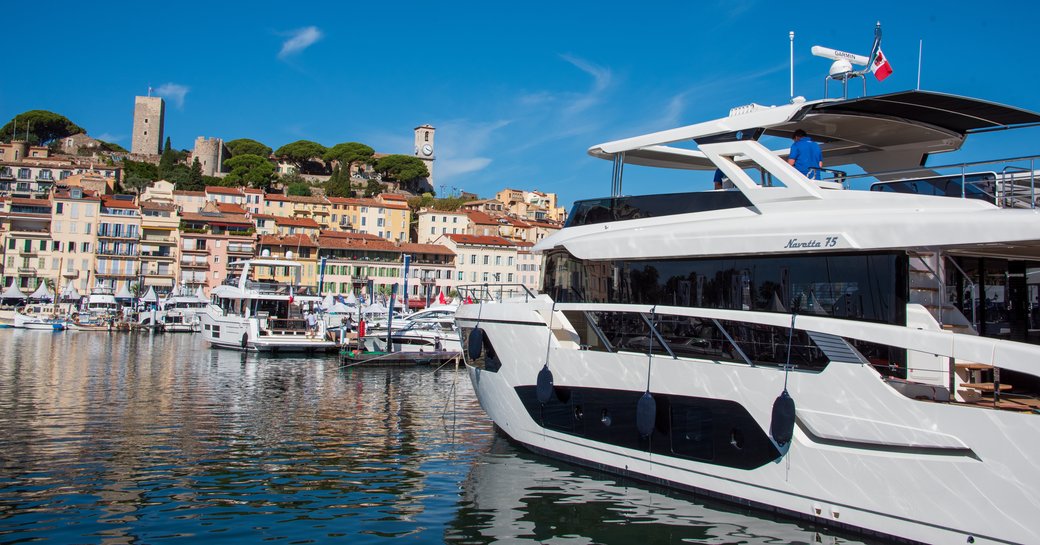 A motor yacht berthed in Vieux Port during the Cannes Yachting Festival, facing towards the marina with Cannes in the background.