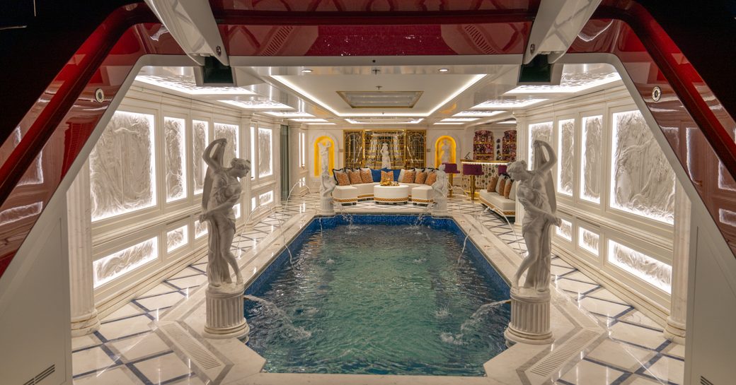 Swimming pool onboard superyacht LEONA with Greek statues to either side and marble flooring. 