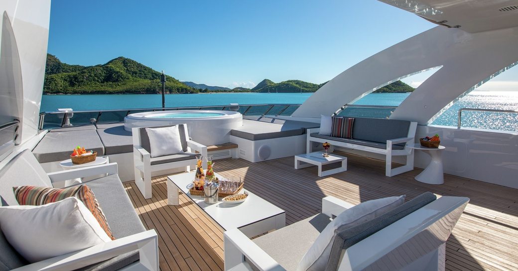 Aft sun deck onboard luxury yacht charter G3, with white upholstered seating arranged to face in towards a low coffee table
