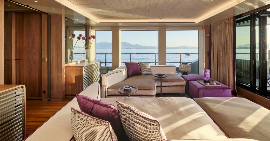 Main salon onboard charter yacht PARA BELLUM, plush lounge area with large windows in the background