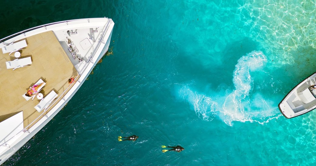 charter guest sunbathes on deck of expedition yacht 'Big Fish' as divers explore beneath the waves