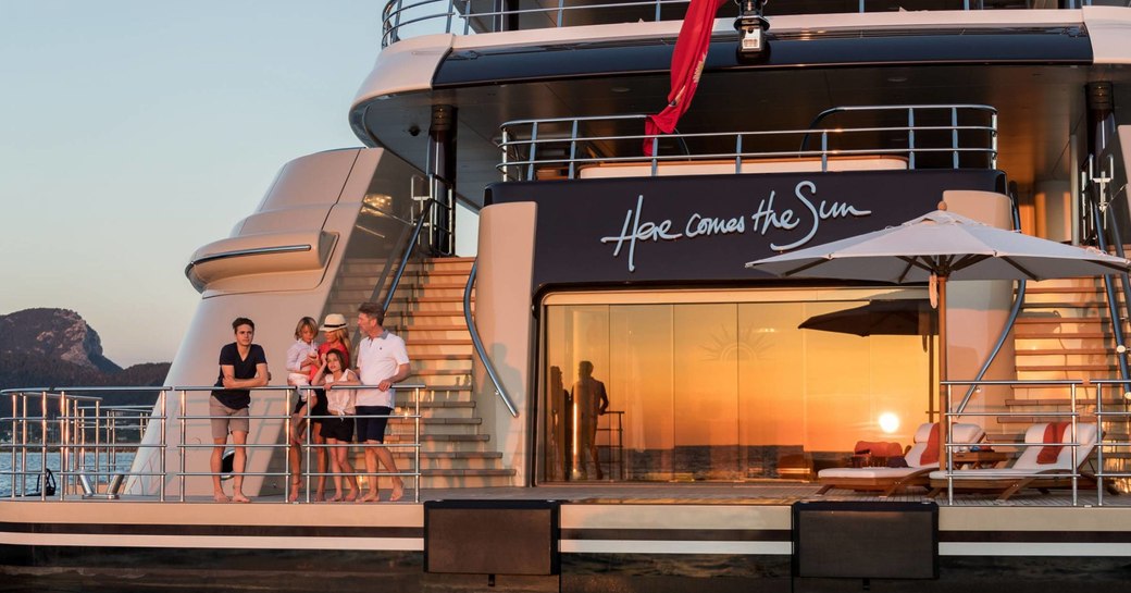 family look out to sea from the swim platform of charter yacht ‘Here Comes The Sun’