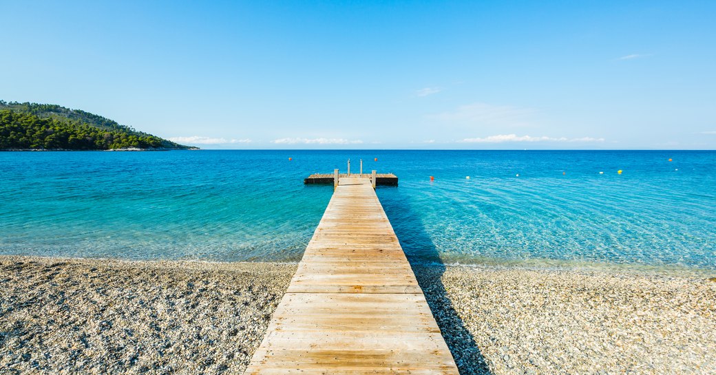 Wooden pier leading out over the turquoise waters on Skopelos island in the Sporades, Greece