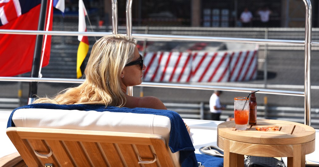 spectator on a sun lounger watches the Monaco Grand Prix from the sundeck of a superyacht berthed in Port Hercules