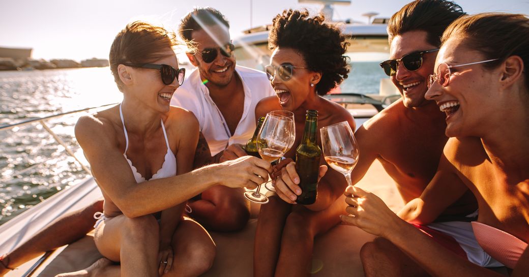 A young group clinking wine glasses on the bow of a yacht