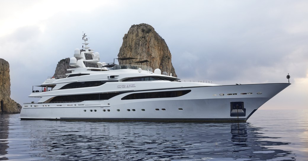 Charter yacht SILVER ANGEL at anchor in a bay with large rocks in the background