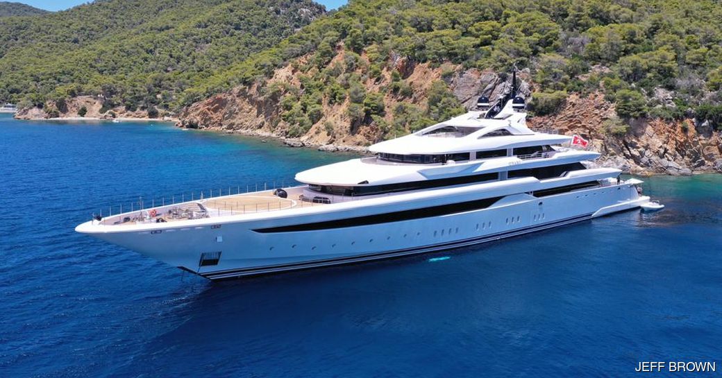 Superyacht O'PARI on water with dramatic coastline in background and two tenders nearby