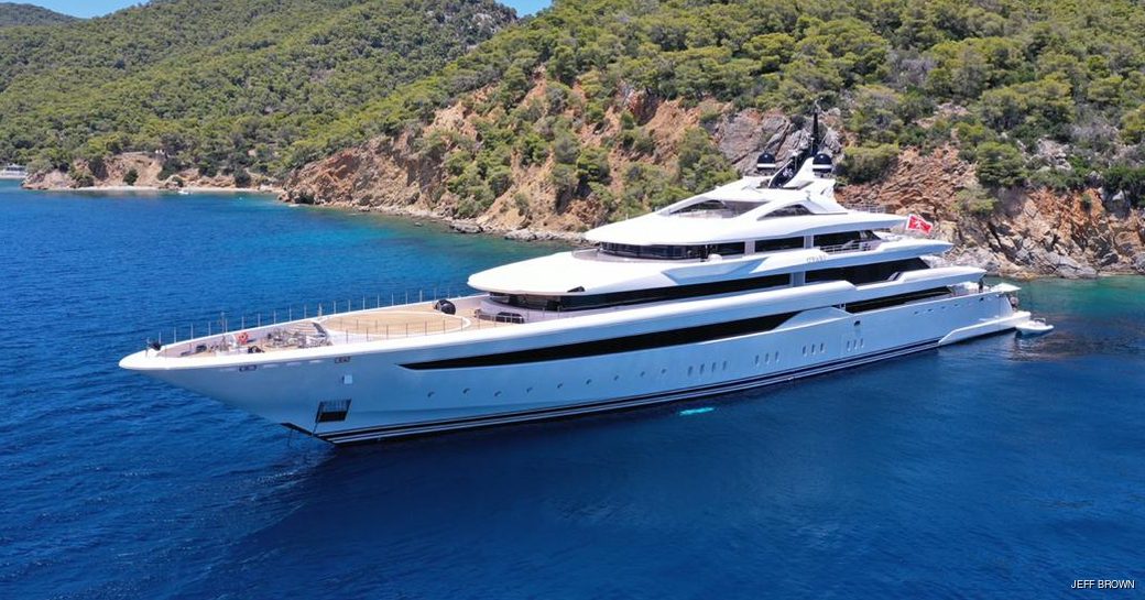Superyacht O'PARI on water with dramatic coastline in background and two tenders nearby