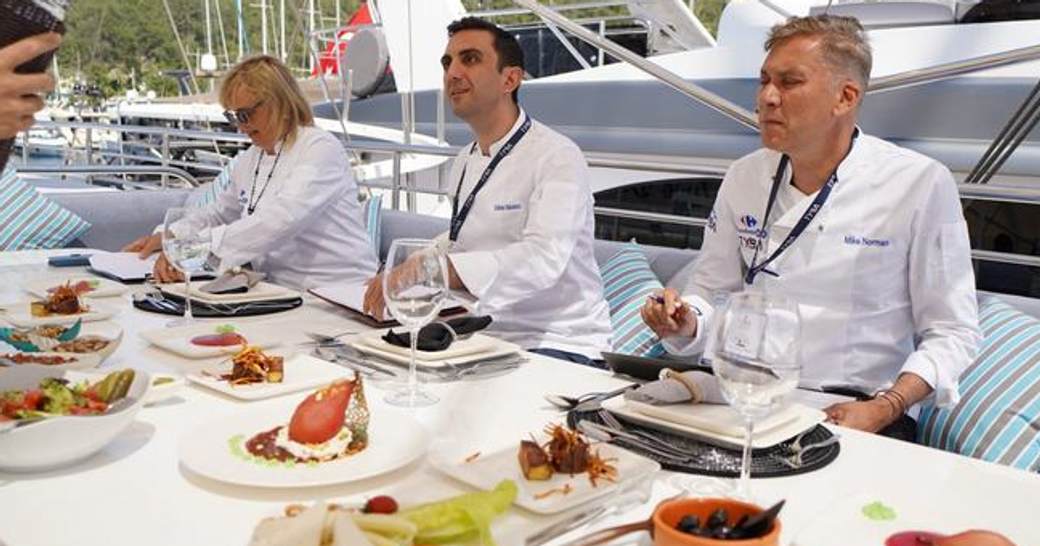 Judges at a table on superyacht with plated dishes
