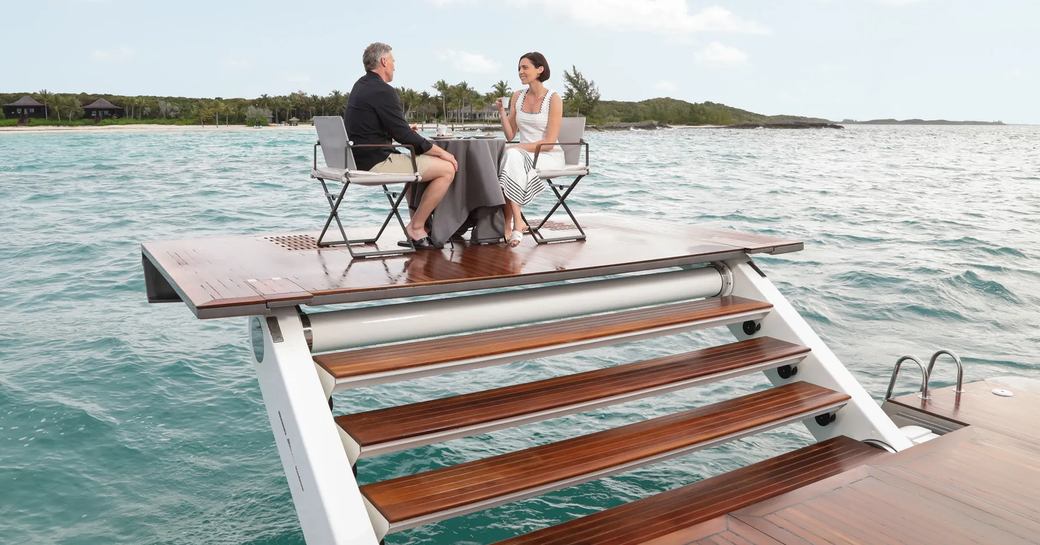 Charter guests having drinks on elevated Z-lift swim platform onboard charter yacht A SALT WEAPON