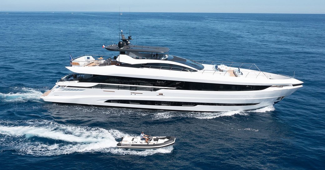 Charter yacht DOPAMINE underway, surrounded by sea with a tender running alongside