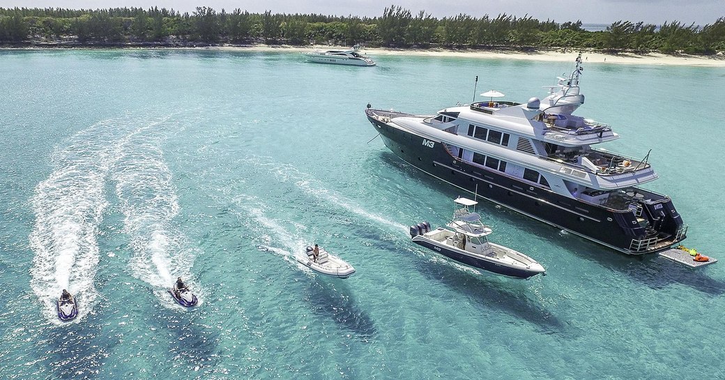 Superyacht M3, with tender and water toys on clear water beside it