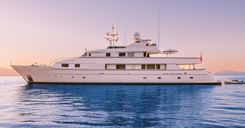 Charter yacht NATALIA V at anchor, surrounded by sea at sunset