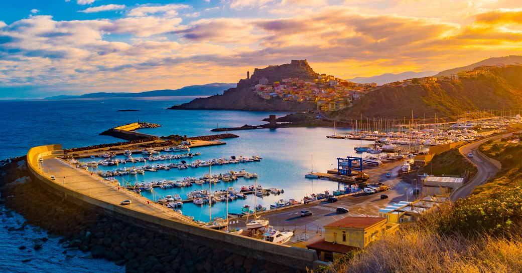 Harbour at sunset in West Mediterranean with rugged hills in background and lots of yachts anchored