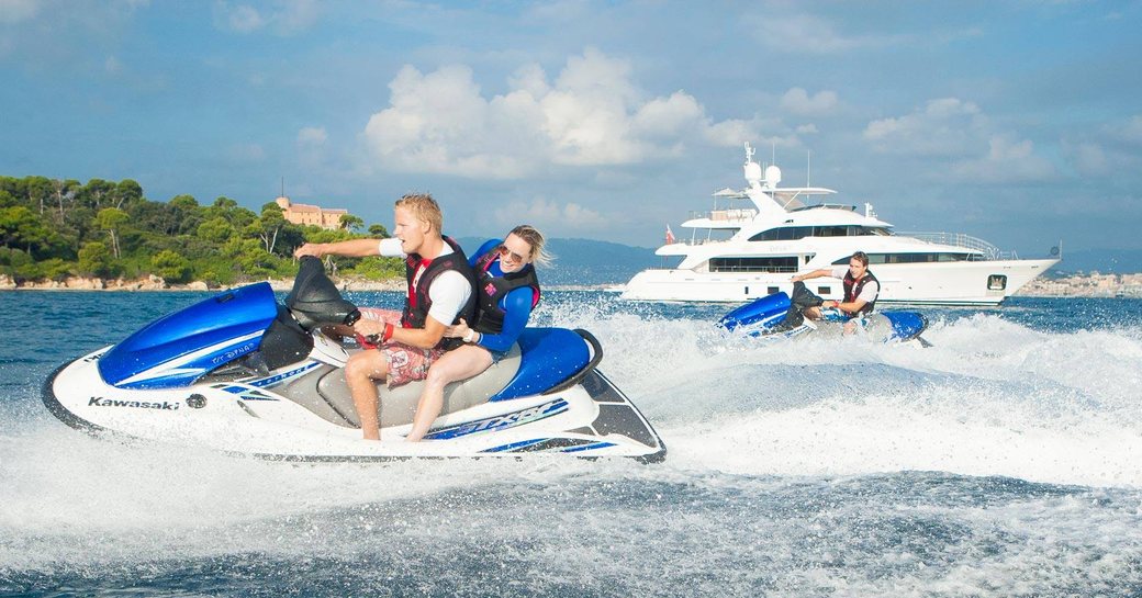 charter guests get out on the jet skis as motor yacht DYNAR looks on