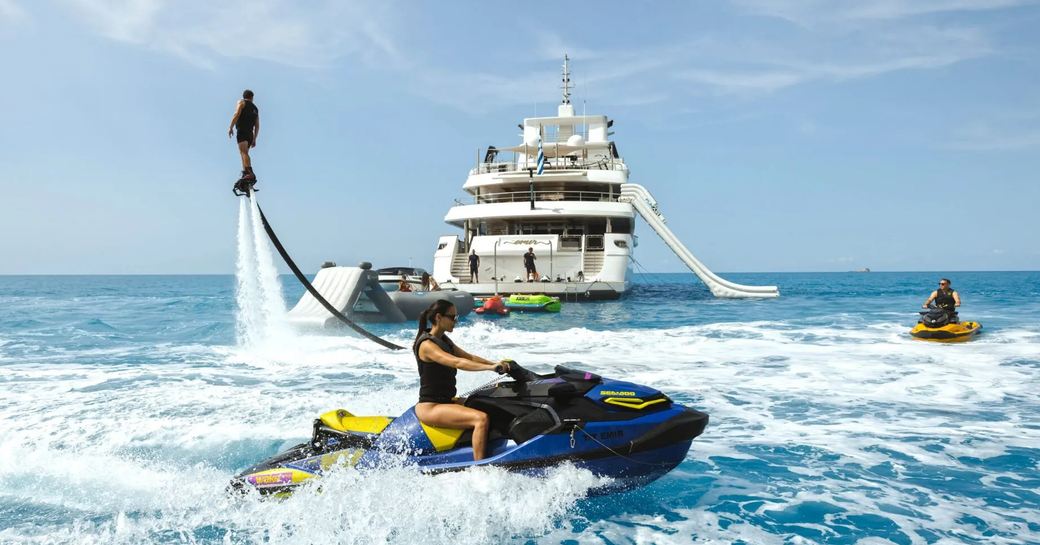 Aft view of luxury charter yacht EMIR at sea with Jet Skis and a flyboard in action