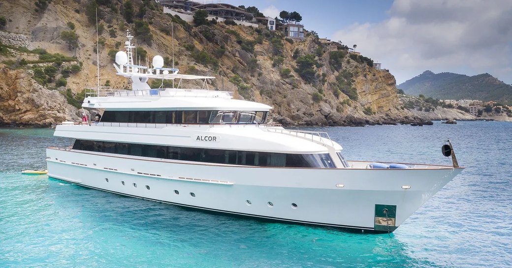 Superyacht charter ALCOR at anchor with cliffs in the background