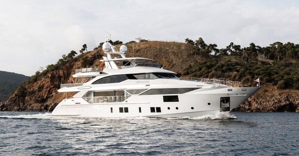 Charter yacht CHARADE underway, with elevated terrain in the background