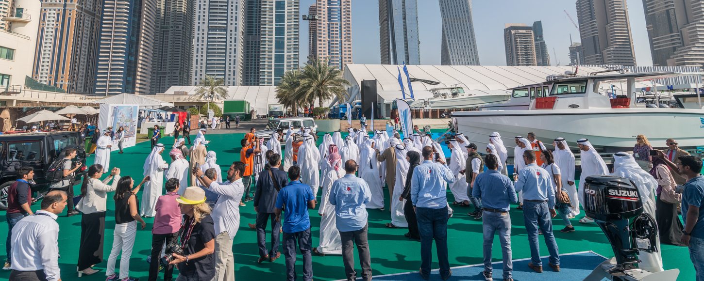 Crowd of people at Dubai International Boat Show with skyscrapers in background