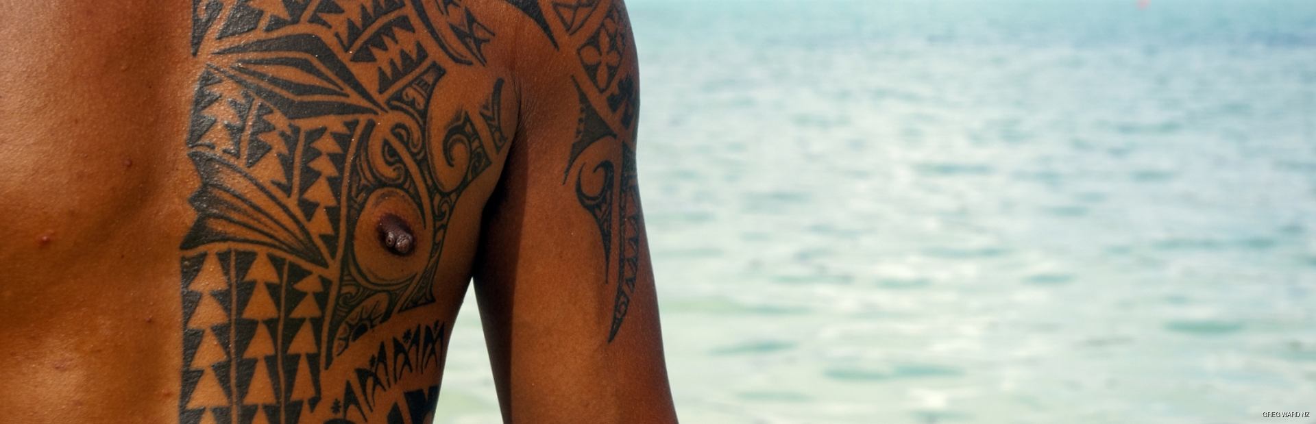A man with a traditional Polynesian tattoos on his arm and chest