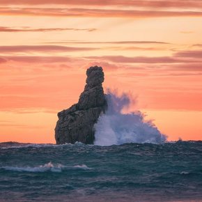 The sun sets while waves crashing against Cap Bernat 
