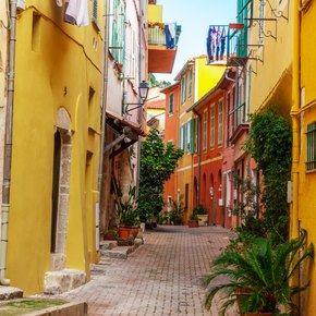 A narrow street with yellow buildings on either side in France