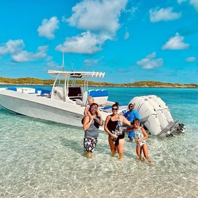 Family posing in front of their charter boat in the water 
