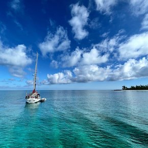 Sailing boat on calm waters under a cloudy blue sky 