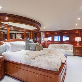 Overview of the master cabin onboard charter yacht MISS STEPHANIE, central berth facing starboard and a flatscreen TV, with a sofa in the background.