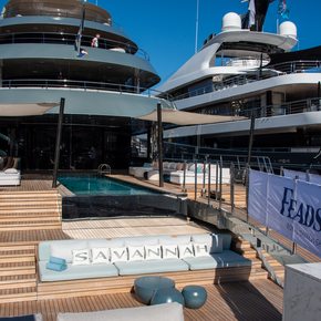 Close up aft view of superyachts docked at Port Hercule with a Feadship banner