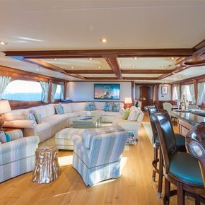 Lounge area onboard charter yacht MISS STEPHANIE, stools looking out of a window to starboard, with a plush seating arrangement to port.