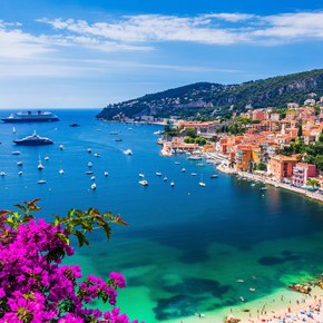 Overview looking down over a bay in the Cote d'Azur, with the sea to port and colored buildings on the shore