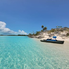 Blue boat moored on white sand by turquoise blue water